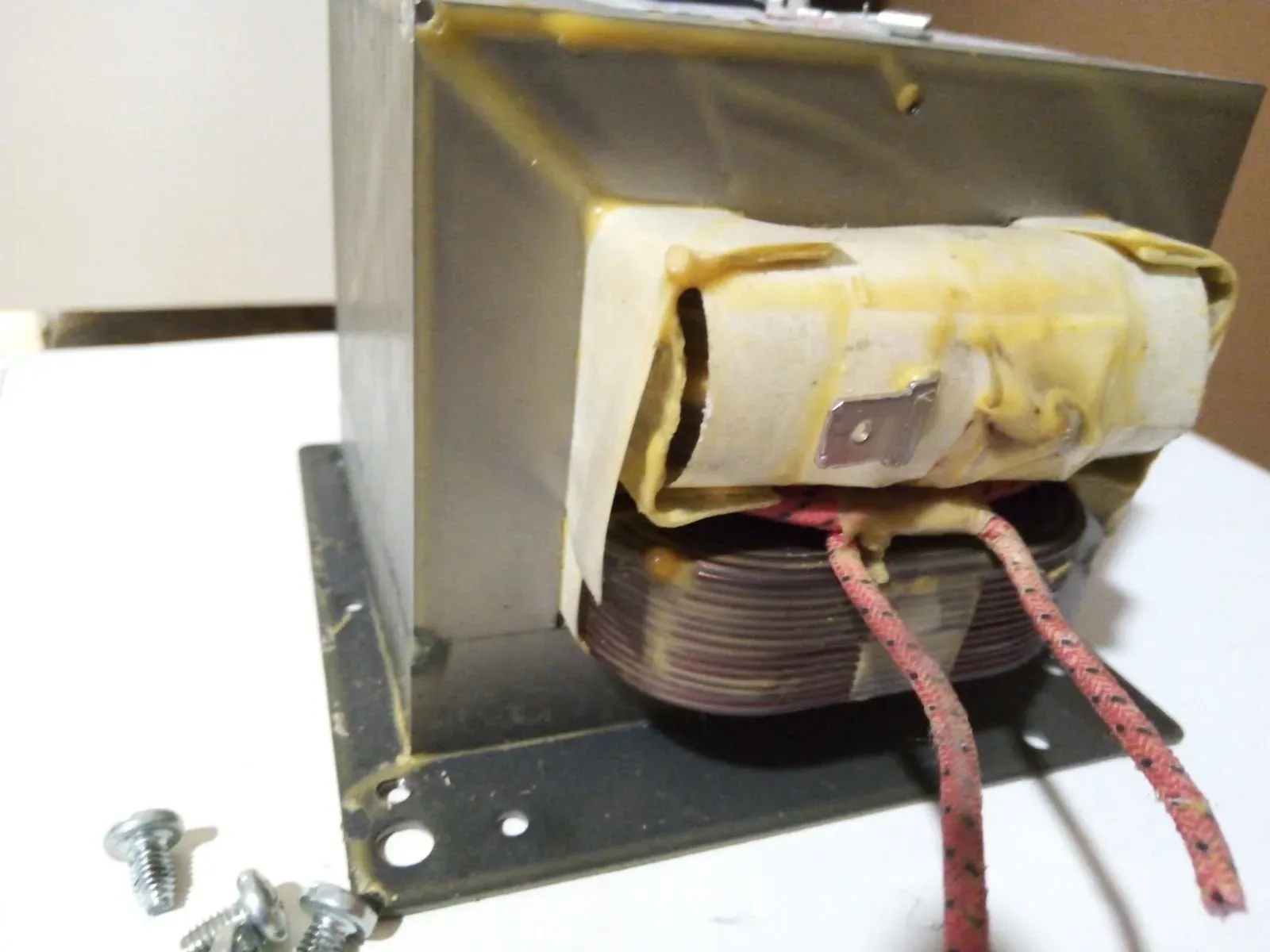 Transformador de microondas extraído, con los tornillos al lado